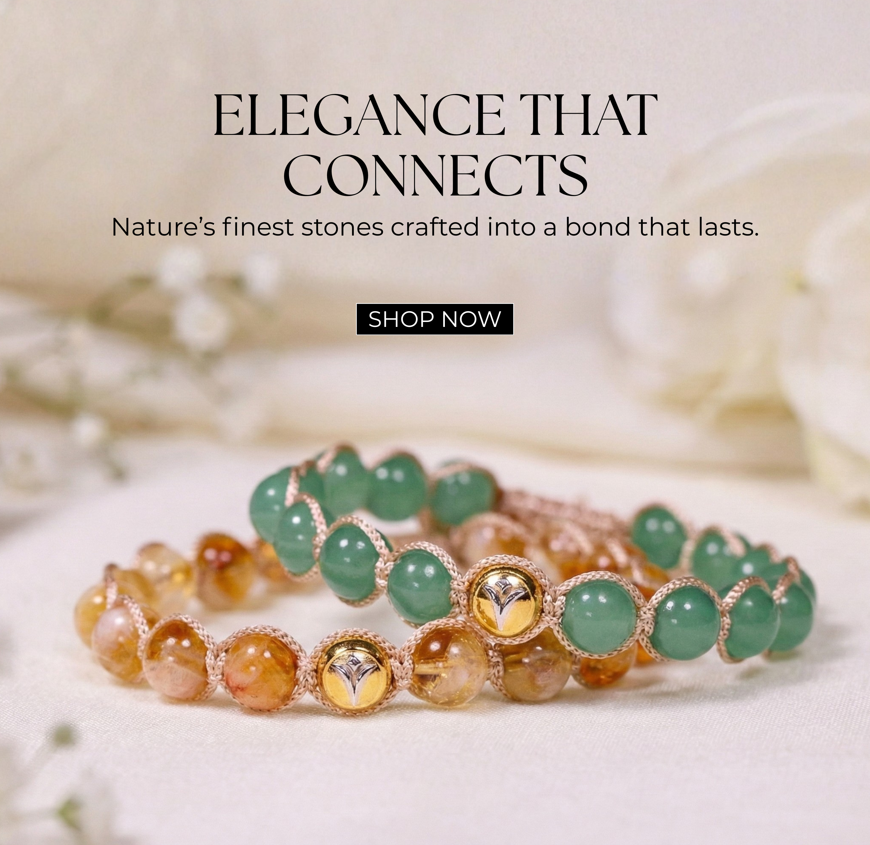 Homepage banner featuring two handcrafted natural gemstone bracelets displayed on a soft fabric background with delicate white flowers. One bracelet is crafted with polished green gemstones, while the other features warm golden and amber-toned natural gemstones. Both bracelets showcase NIVI's signature 925 sterling silver centerpiece with one-micron gold plating, highlighting timeless craftsmanship, meaningful design, and everyday elegance. The banner includes the message "Elegance That Connects – Nature's 